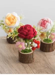 Close-up of three handmade crochet rose potted plants with natural wooden bases
