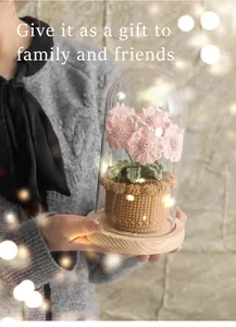 Detail of handmade crochet pink daisy flowers in a glass dome with wood base