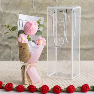 Close-up of handmade pink knitted tulip and daisies in a premium gift box with ribbon