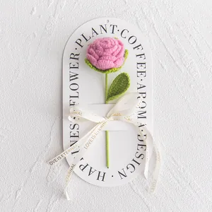 Detail of hand-crocheted pink rose with green stem and Love Is Eternal gold ribbon