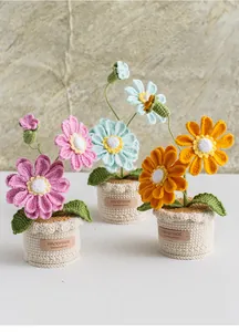 Handmade crochet zinnia potted plants with leather handmade labels on stone background