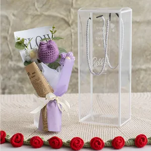 Detail of handmade knitted tulip bouquet inside a transparent portable gift box with ribbon