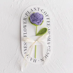 Close-up of handmade purple crochet rose with love ribbon on a branded card