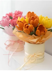 Nahaufnahme handgehäkelter Tulpensträuße in rosa, orangen und gelben Geschenkboxen