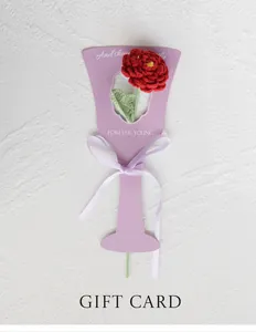 Gros plan d'une rose rouge au crochet faite main avec ruban sur support carte cadeau