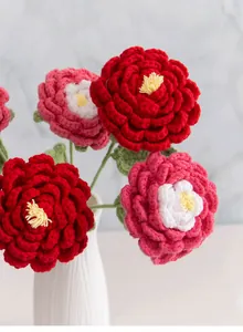Gros plan d'un bouquet de pivoines au crochet fait main dans un vase blanc strié