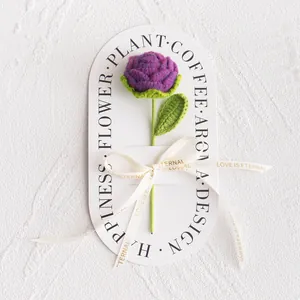 Detailed view of hand-knitted purple rose with leaves and Love Is Eternal ribbon