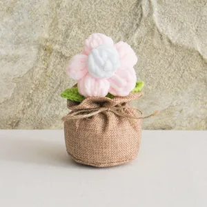 Detail of handmade crochet puff flower in a rustic burlap bag with green knitted leaves