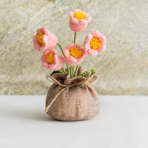 Close-up of handmade pink crochet lily flowers in a rustic burlap bag with bow