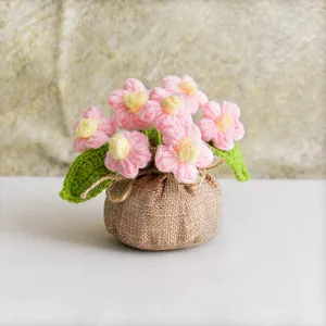 Macro detail of handmade crochet pink flowers in a rustic linen wrapped pot decoration