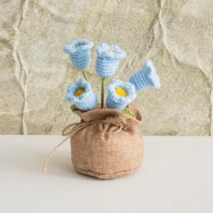 Close-up of handmade crochet lily of the valley in a rustic burlap sack pot