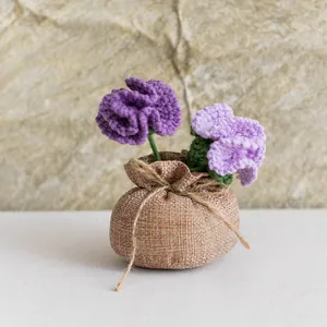 Détail d'un œillet au crochet violet fait main dans un pot en toile de jute rustique