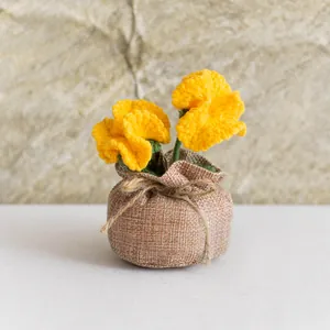 Détail d'oeillets jaunes au crochet faits main dans un pot en toile de jute rustique