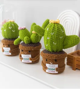 Détail d'un mini cactus en peluche tricoté main avec carte de motivation pour décoration de bureau