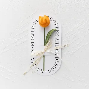 Close-up of handmade crochet orange tulip with green stem and Love Is Eternal ribbon