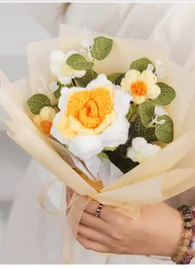 Handheld crochet bouquet with yellow roses and eucalyptus leaves in soft paper wrap