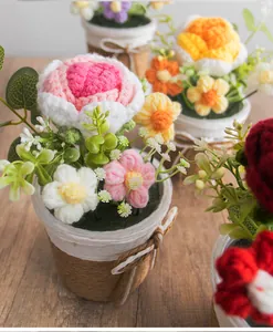 Detailansicht handgehäkelter Blumen in bunten Farben mit rustikalem gewebtem Blumentopf