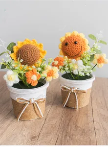 Detail von zwei handgehäkelten Sonnenblumen-Topfpflanzen mit Lächeln auf einem Holztisch