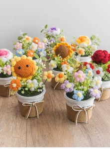 Detail handgefertigter Häkel-Sonnenblumen- und Rosen-Topfpflanzen mit Juteschleifen