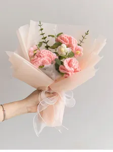Detail of hand-crocheted pink carnations and white daisies wrapped in soft pink paper