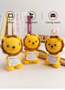 Detailed view of handmade crochet lions holding positive cards on a wooden desk