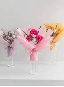 Detail of three handmade crochet bouquets with roses and sunflowers on white iron stands