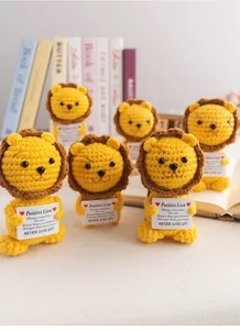 Close-up of handmade crochet lions with positive quote cards for desktop decoration