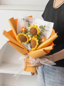 Detail of hand-crocheted sunflower bouquet with orange gift wrap and white ribbon