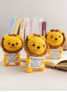 Macro detail of handmade crochet lion doll with positive quote card on bookshelf
