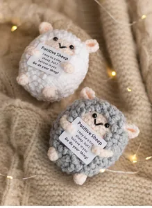 Close-up of cute knitted positive sheep with motivational cards on warm lights