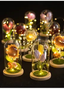 Vue détaillée de tournesols et tulipes au crochet faits main sous dôme en verre et LED