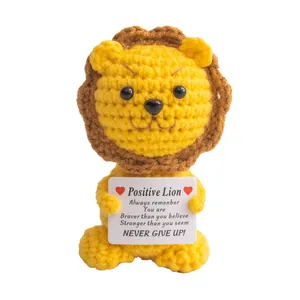 Handmade crochet lion plush doll holding a positive encouragement card on white background