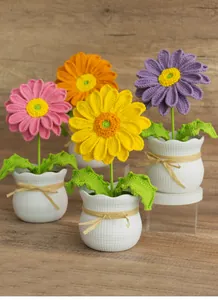Détail de quatre marguerites en crochet faites main dans des pots en céramique à carreaux