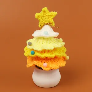 Detailed view of handmade crochet Christmas tree with tiered yellow yarn and colorful pom poms
