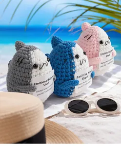 Detailed knit texture of handmade crochet shark dolls with positive message cards on a beach
