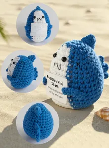 Close-up of handmade crochet shark doll with positive message card and beach detail
