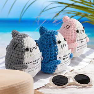 Handmade crochet sharks holding positive cards on a tropical beach background