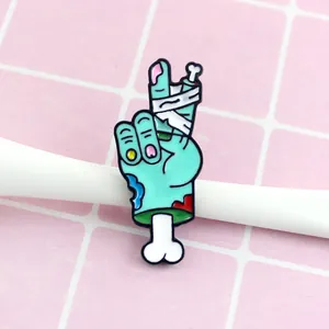Detail of blue skull hand enamel pin with white bandage and pink nails on pink grid