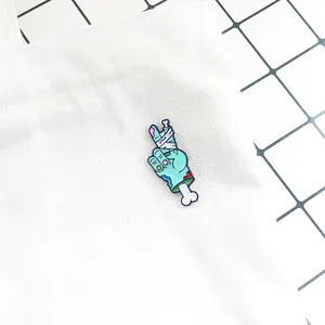 Detail shot of a blue zombie hand enamel pin with bandages on a white canvas bag