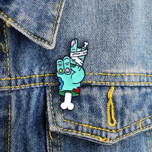 Zombie hand enamel pin showing victory sign on blue denim jacket pocket
