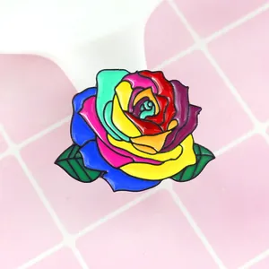 Colorful rainbow rose enamel pin badge with green leaves on light pink tile background