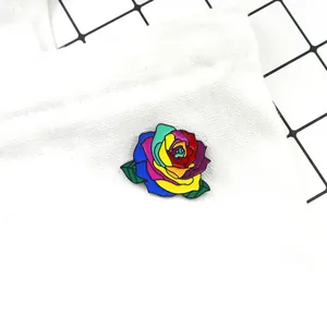 Detailed macro view of a vibrant rainbow enamel rose pin on white canvas material