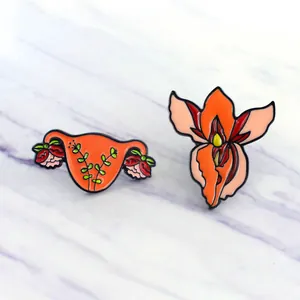 Feminist anatomical uterus and floral orchid enamel brooch set on marble background