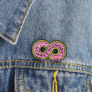 Pink infinity doughnut enamel pin with Always Hungry text on blue denim jacket