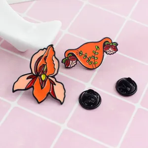 Detailed macro view of two enamel pins featuring iris flower and floral uterus designs