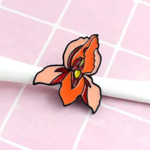 Detailed macro view of an artistic uterus flower enamel pin with vibrant orange and red colors