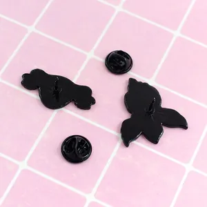 Uterus shaped black enamel brooches back view with butterfly clasps on checkered pattern