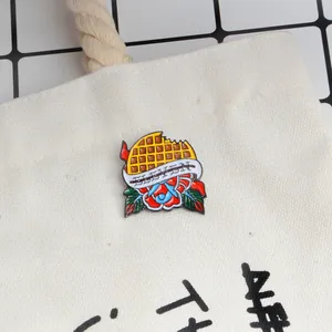 Detail of Eleven enamel waffle brooch pinned on a canvas bag for denim jacket styling
