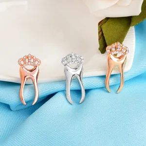Three creative tooth crown brooches in gold, silver and rose gold with rhinestones