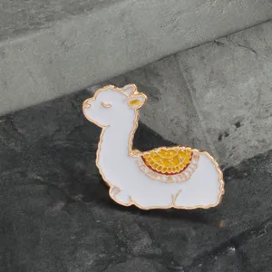 Vue détaillée d'une broche lama en émail blanc avec bords dorés et motifs colorés